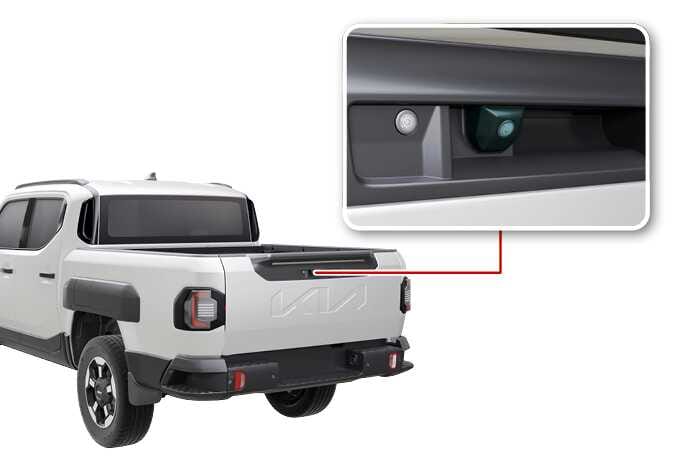 2026 기아 타스만 광각-후방 카메라 이미지입니다. 차량 후면 테일게이트 핸들 부분을 붉은색 선으로 연결하여 확대한 상세도가 있습니다. 상세도에는 청록색으로 강조된 카메라 렌즈가 테일게이트 버튼 우측에 위치해 있습니다. 후방 모니터 작동을 위한 인식 센서의 장착 위치를 설명합니다.