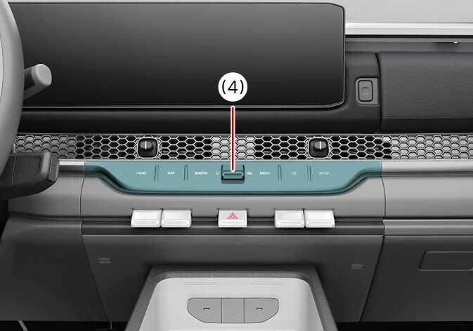 2026 기아 타스만 인포테인먼트 시스템 작동 버튼 이미지입니다. 센터페시아 중앙에 청록색으로 강조된 조작 패널이 위치하며, 붉은색 지시선이 포함된 번호 (4)가 패널 중앙의 볼륨 및 전원 조절 노브를 가리키고 있습니다. 인포테인먼트 시스템을 작동시키는 버튼의 위치를 설명합니다.