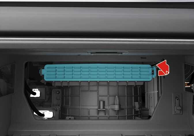 This image shows the air filter holder cover for the 2026 Kia Tasman climate control unit. The red arrow on the right side of the filter cover, highlighted in turquoise, indicates an outward pull. This explains how to remove the cover by pressing the right side of the cover and pulling in the direction of the arrow.