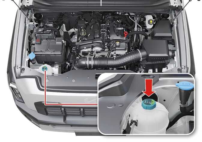 2026 기아 타스만 엔진 냉각수 리저버 탱크 이미지입니다. 엔진룸 내부 전경과 함께 냉각수 탱크 캡을 확대한 상세도가 포함되어 있습니다. 상세도에는 굵은 빨간색 화살표가 아래쪽을 향하며 청록색으로 강조된 캡 상단을 가리키고 있습니다. 냉각수 보조 탱크 캡의 돌기가 정상적으로 안착되었는지 확인하는 위치를 설명합니다.