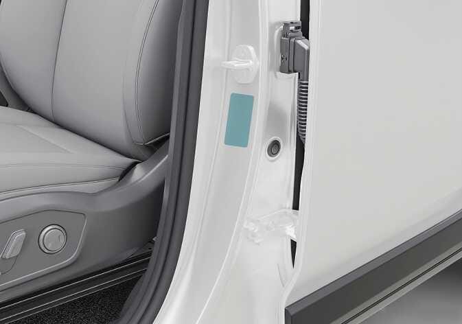 2026 기아 타스만 자기 인증 라벨 위치 이미지입니다. 운전석 도어를 열었을 때 보이는 차체 중앙 기둥(B필러) 하단에 직사각형 라벨이 청록색으로 강조되어 있습니다. 차량이 대한민국 자동차 관리 법령에 적합하게 제작되었음을 나타내는 라벨의 부착 위치를 설명합니다.