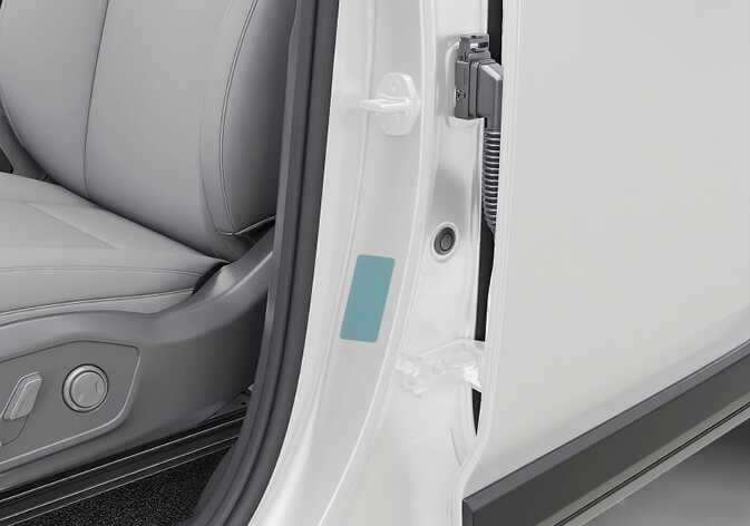 2026 기아 타스만 타이어 공기압 라벨 위치 이미지입니다. 운전석 시트 우측의 센터 필러에 부착된 사각형 라벨이 청록색으로 강조되어 표시되어 있습니다. 차량의 권장 타이어 공기압 정보를 확인할 수 있는 라벨의 부착 위치를 설명합니다.