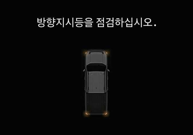 2026 기아 타스만 LCD 표시창 경고 메시지 이미지입니다. 검은색 배경 상단에 '방향지시등을 점검하십시오.'라는 문구가 표시되어 있고, 차량 평면도 이미지의 전후좌우 네 모서리에 주황색 조명이 켜진 상태가 시각화되어 있습니다. 방향지시등 작동에 문제가 발생했을 때 운전자에게 점검을 안내하는 화면 구성을 설명합니다.