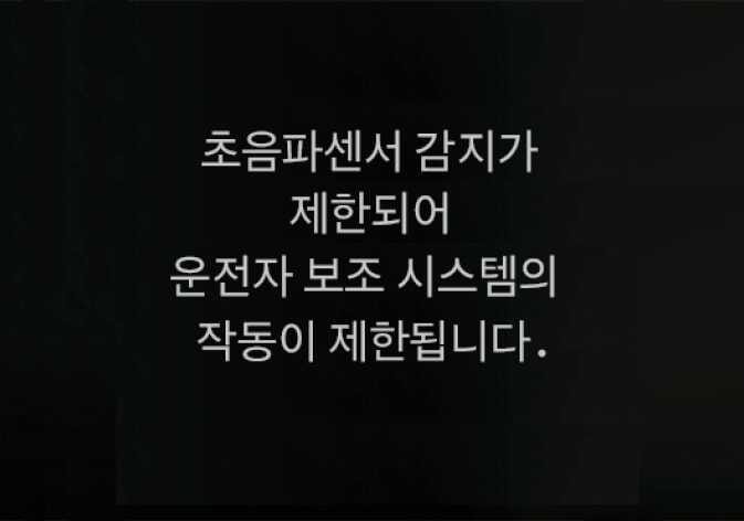 2026 기아 타스만 인식 센서 가림 경고 메시지 이미지입니다. 검은색 배경의 클러스터 화면 중앙에 흰색 텍스트로 '초음파센서 감지가 제한되어 운전자 보조 시스템의 작동이 제한됩니다.'라는 문구가 표시되어 있습니다. 초음파센서에 이물질이 묻거나 가려져 시스템 작동이 제한될 때 표시되는 안내 문구를 설명합니다.