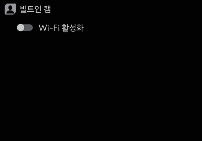 This is an image of the 2026 Kia Tasman built-in cam settings screen. The text 'Built-in Cam' appears at the top of the screen on a black background, with the text 'Enable Wi-Fi' and a toggle switch below it. This explains the menu structure for activating the Wi-Fi function to connect the phone app to the vehicle.
