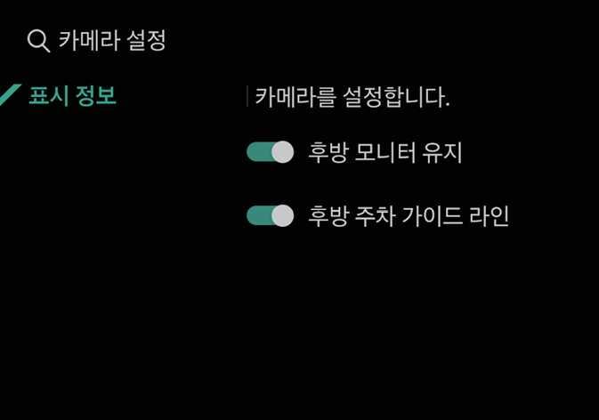 2026 기아 타스만 인포테인먼트 시스템의 카메라 설정 메뉴 이미지입니다. 화면 좌측에 '표시 정보' 탭이 청록색으로 강조되어 선택된 상태입니다. 우측에는 '후방 모니터 유지'와 '후방 주차 가이드 라인' 항목이 있으며, 각 항목의 설정 스위치가 켜짐 상태로 표시되어 있습니다. 후방 모니터 영상 유지 여부와 주차 가이드 라인 표시 여부를 설정하는 기능을 설명합니다.