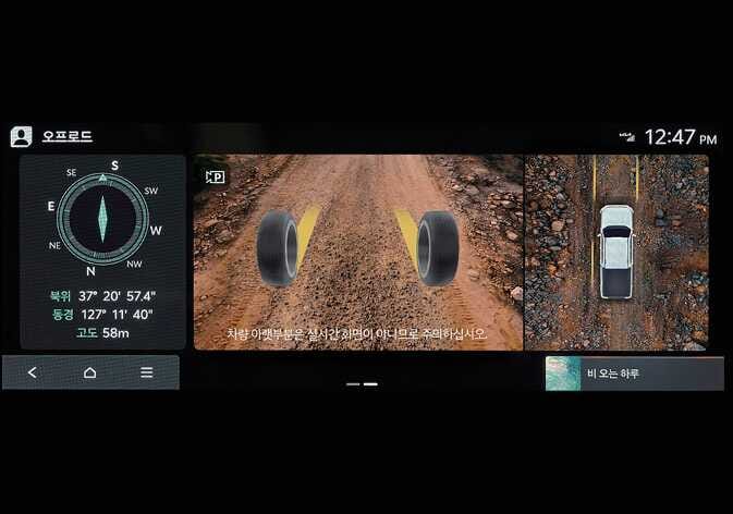 2026 기아 타스만 오프로드 모드의 그라운드 뷰 모니터 실행 화면 이미지입니다. 좌측에는 나침반, 위도, 경도, 고도 정보가 표시되고, 중앙 화면에는 타이어의 위치와 노면 상태가 시각화되어 있습니다. 화면 하단에는 '차량 아랫부분은 실시간 화면이 아니므로 주의하십시오'라는 경고 문구가 있습니다. 차량 전방 하부의 상황을 모니터로 제공하여 험로 주행을 돕는 화면 구성을 설명합니다.